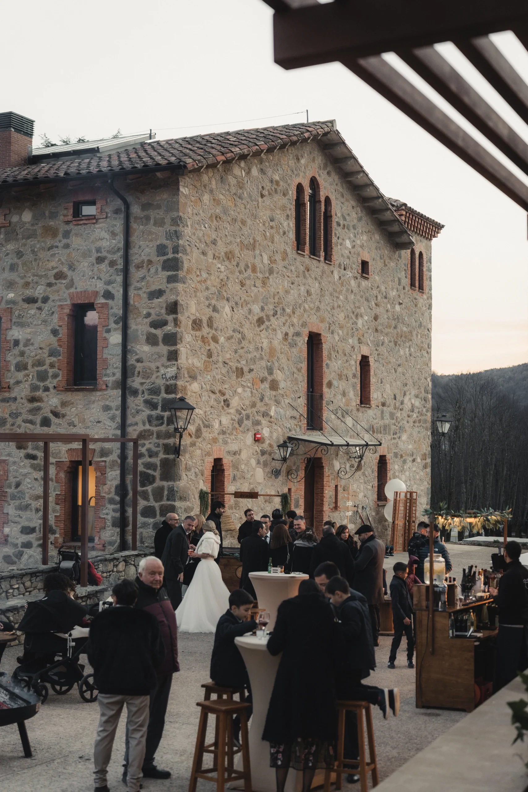 Convidats gaudint de l'aperitiu d'un casament a l'aire lliure al pati exterior de la masia rural Mas Pairó a Camprodon.